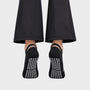 Bodiwealth Black cross strap yoga socks, back and grip on model