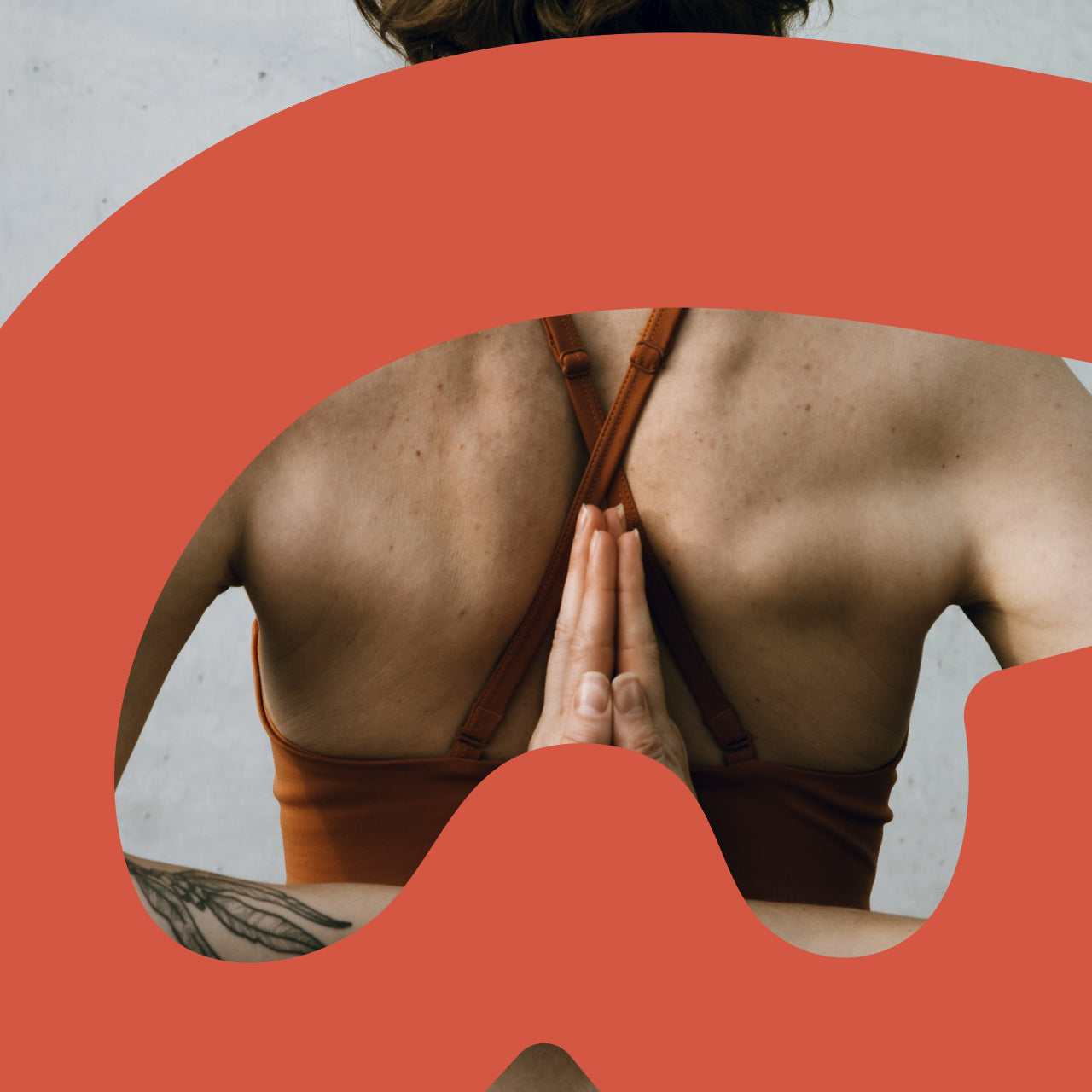 Person in a brown bikini top performing a yoga prayer pose with hands pressed together at chest, back view, framed by an orange curved Bodywealth logo element against a neutral background.